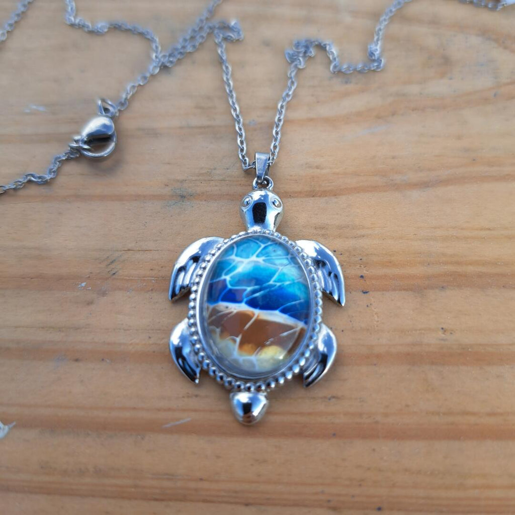 Exquisite hand-painted beach scene turtle pendant. Durable stainless steel with 17" chain. Gulf Coast artisan jewelry.