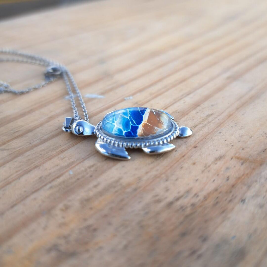 Exquisite hand-painted beach scene turtle pendant. Durable stainless steel with 17" chain. Gulf Coast artisan jewelry.