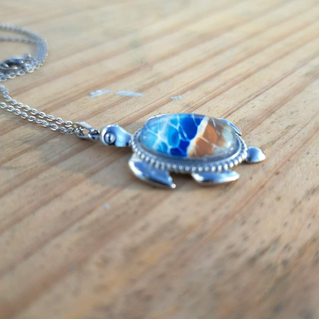Exquisite hand-painted beach scene turtle pendant. Durable stainless steel with 17" chain. Gulf Coast artisan jewelry.