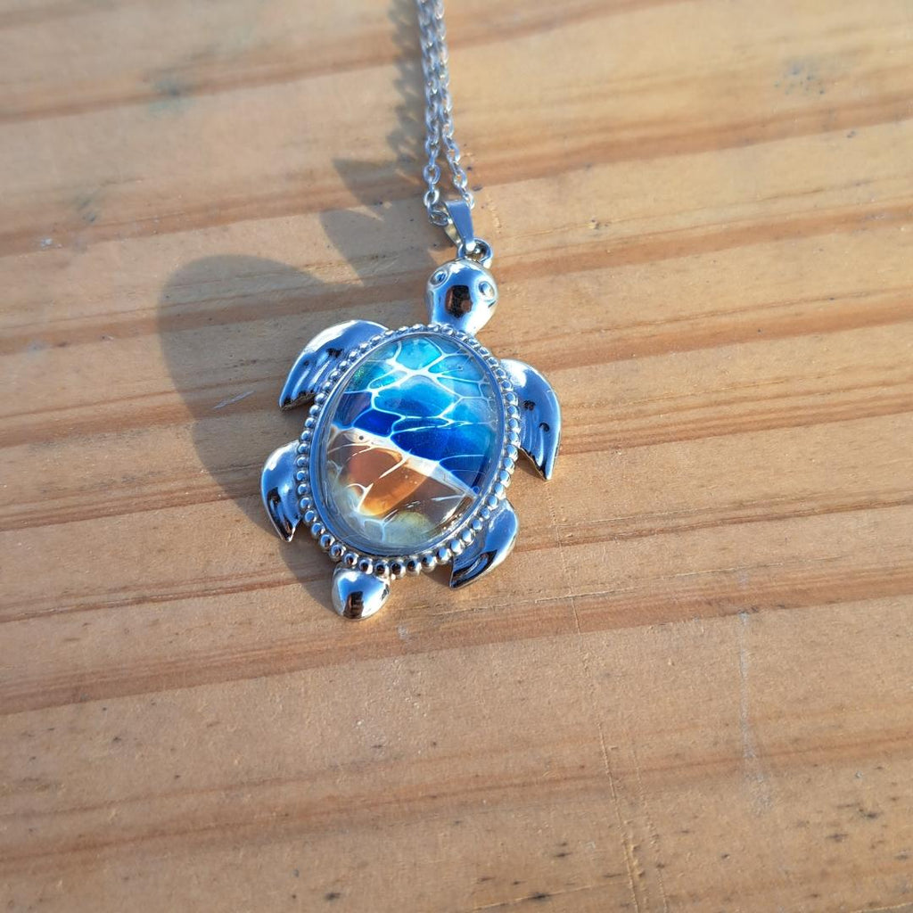 Exquisite hand-painted beach scene turtle pendant. Durable stainless steel with 17" chain. Gulf Coast artisan jewelry.