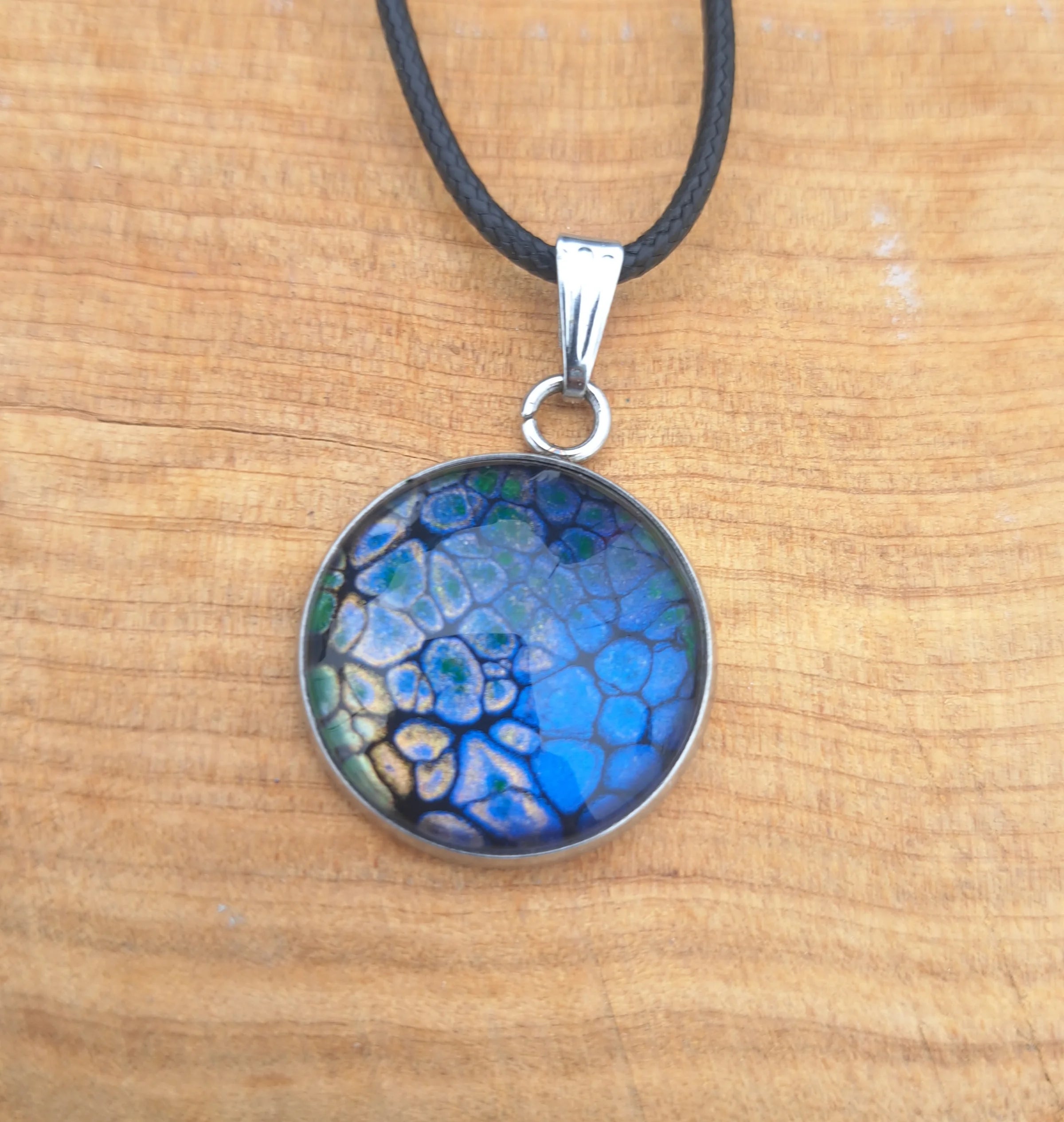 Stunning deep blue pendant with dragon scale pattern in emerald & gold. 20mm stainless steel on 18" cord.