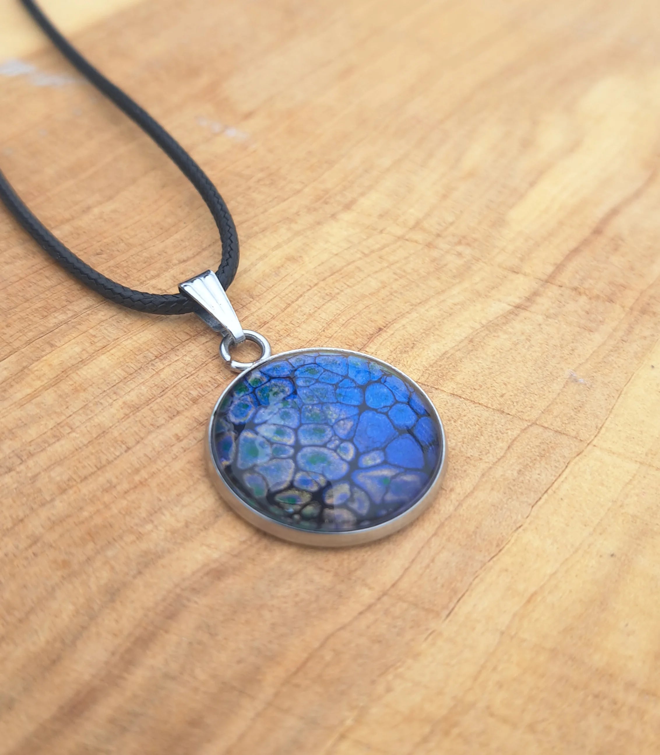 Stunning deep blue pendant with dragon scale pattern in emerald & gold. 20mm stainless steel on 18" cord.
