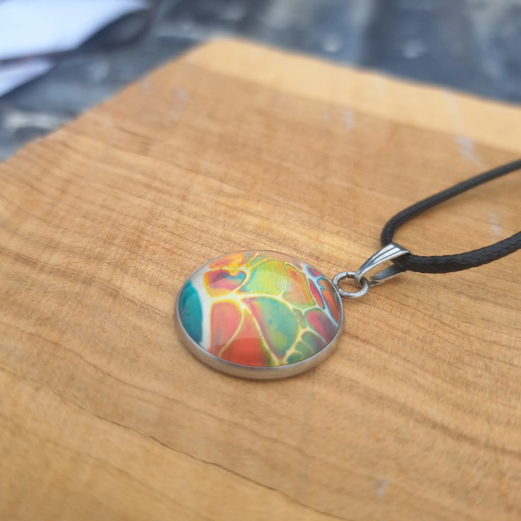 Vibrant rainbow pendant with stained glass effect. Bold artistic statement jewelry on 18" black cord.